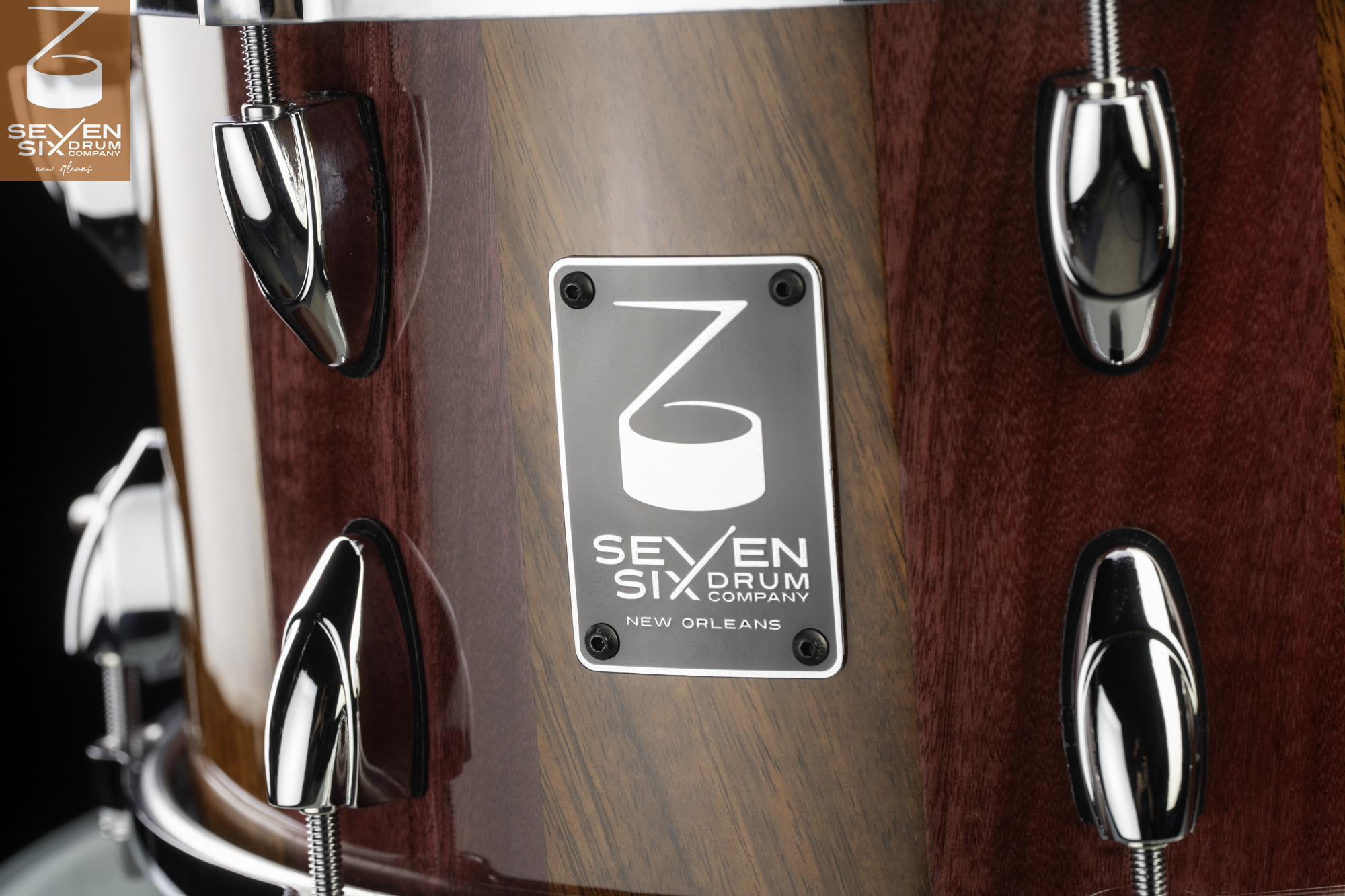 Handmade wood snare drum with a glossy striped finish, polished chrome lugs, and a metal Seven Six Drum Company badge.