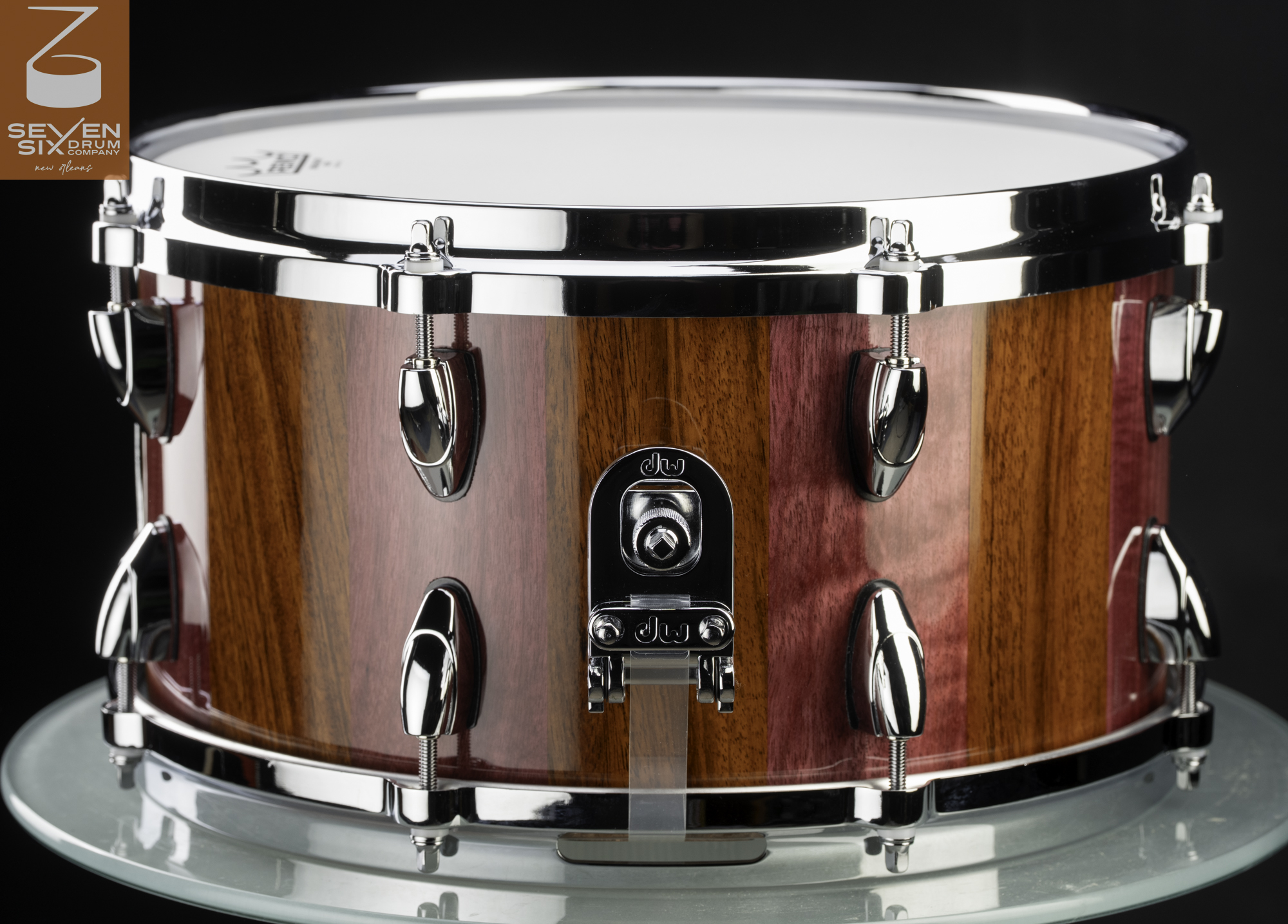 Handmade snare drum with a glossy purple and brown striped wood shell, chrome rims, teardrop lugs, and a DW butt plate.