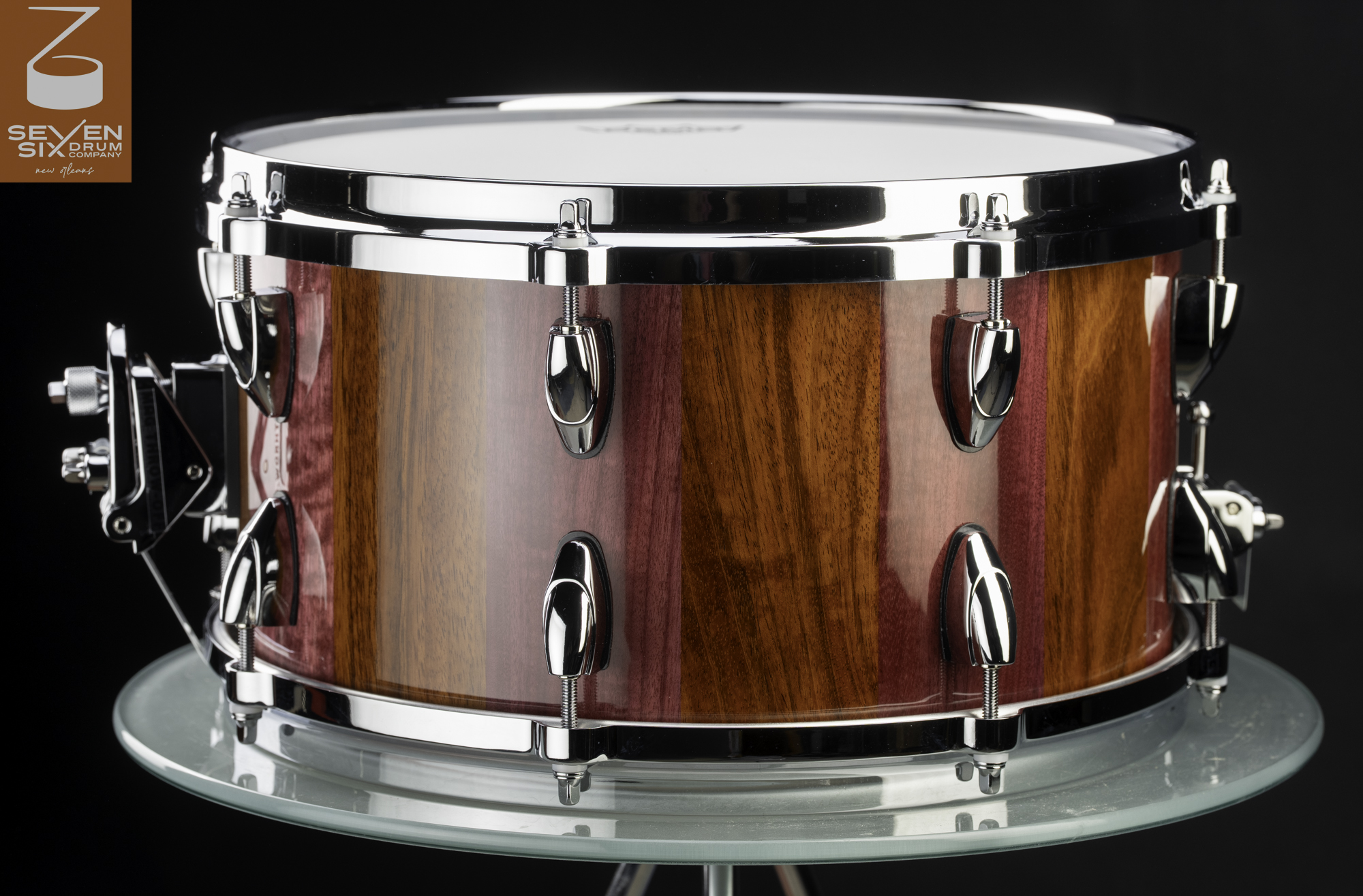 Handmade snare drum with a glossy striped purple and brown wood shell, polished chrome lugs, and chrome hoops.