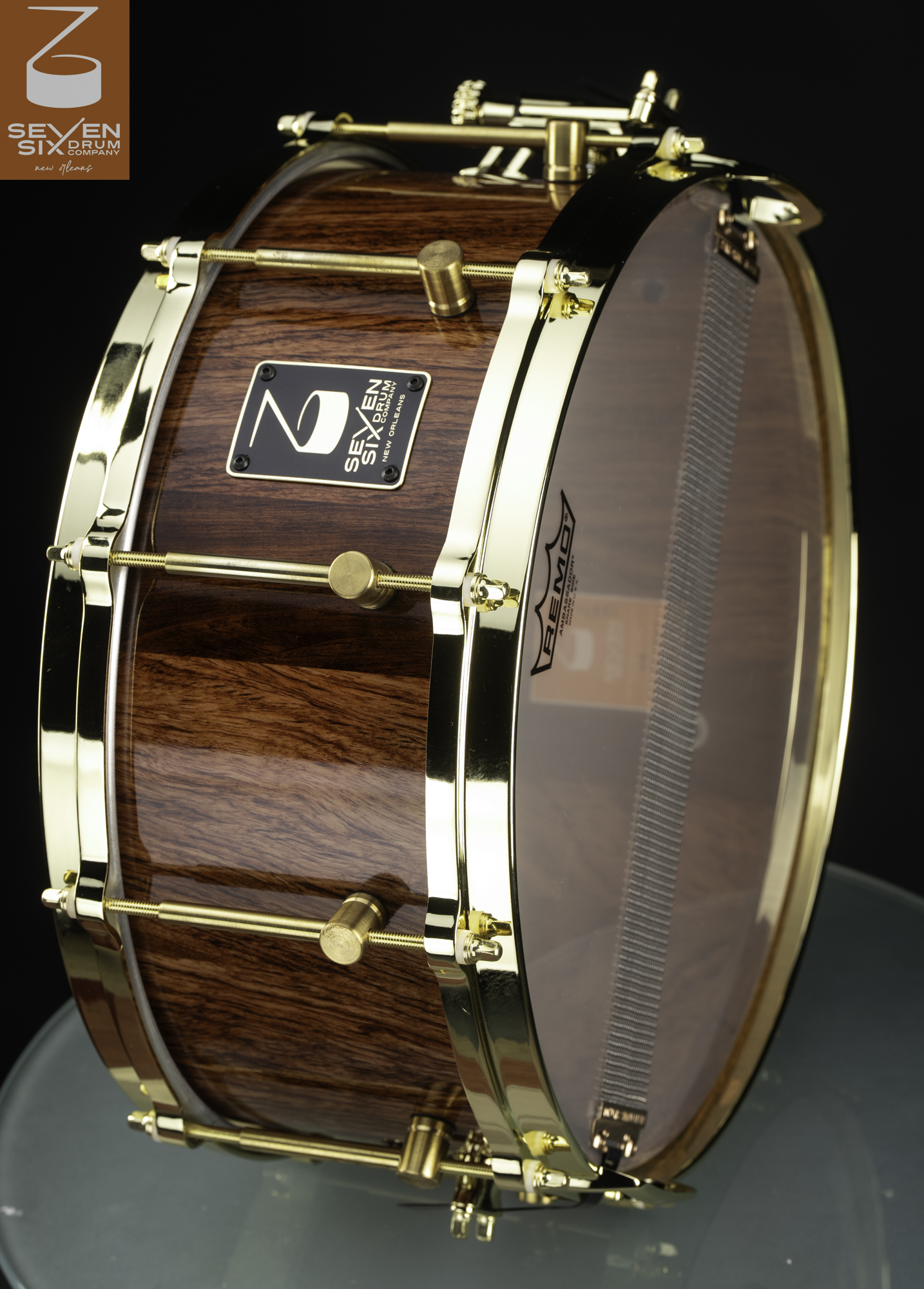 Handmade snare drum featuring a high-gloss natural wood grain shell with polished gold hoops and hardware.