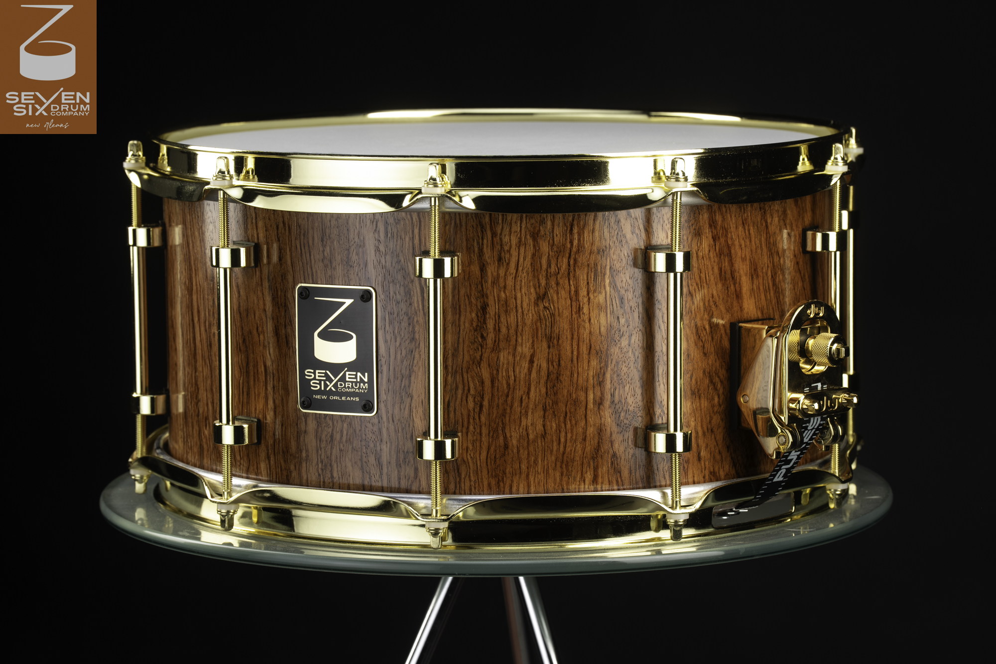 Handmade wood snare drum featuring a natural grain finish with polished gold hoops, tube lugs, and a gold throw-off.