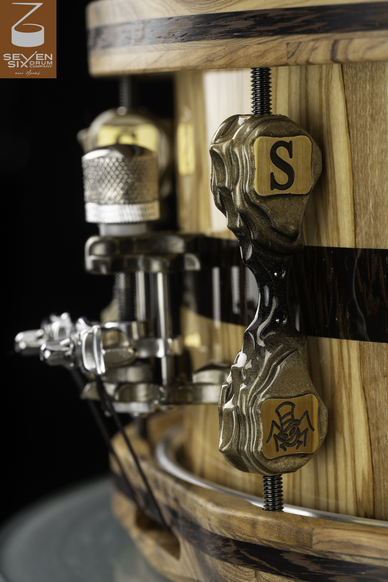 Natural wood snare drum with wood hoops, a custom sculpted gold lug, and a chrome strainer.