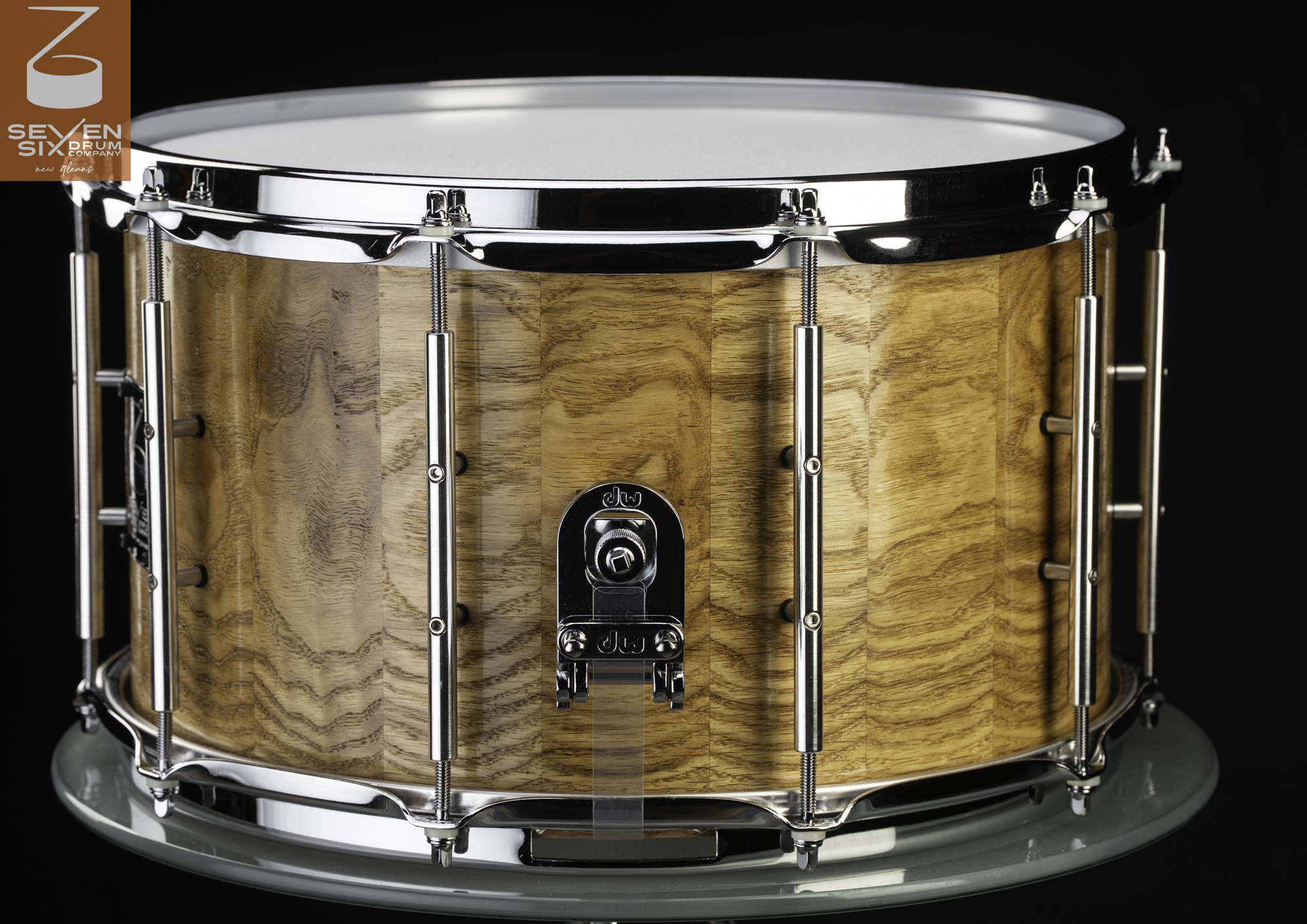Glossy natural oak stave snare drum featuring chrome tube lugs, triple-flanged hoops, and DW hardware.