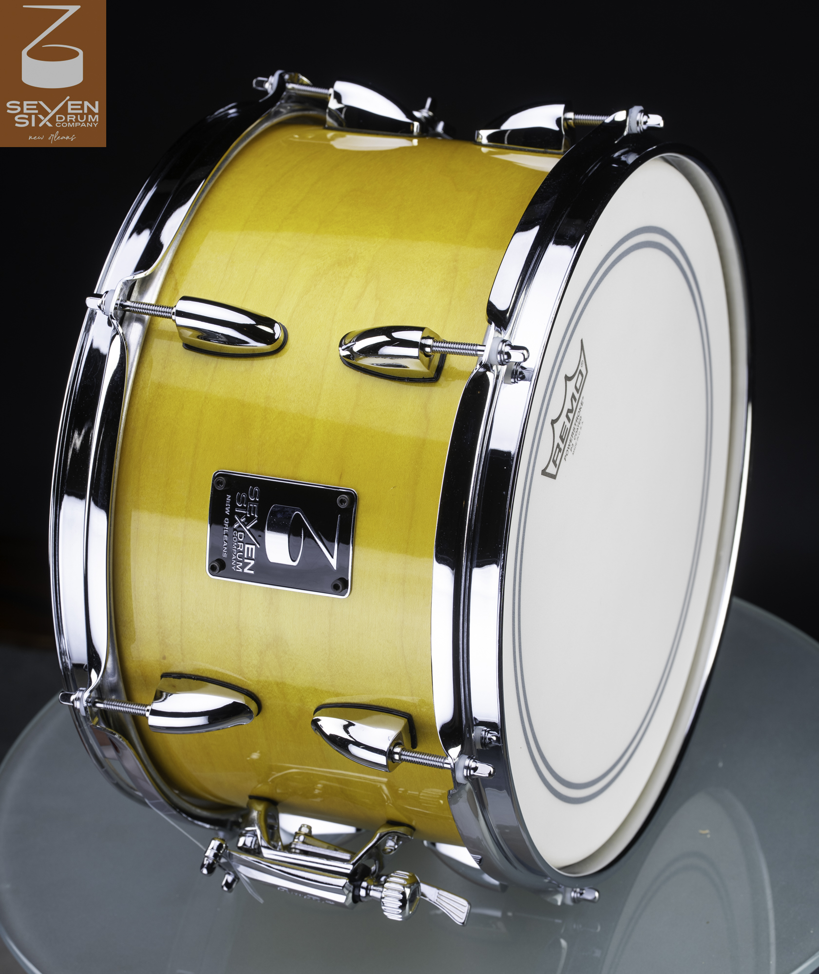 Handmade snare drum with a glossy yellow wood shell, chrome hoops, teardrop lugs, and throw-off strainer.