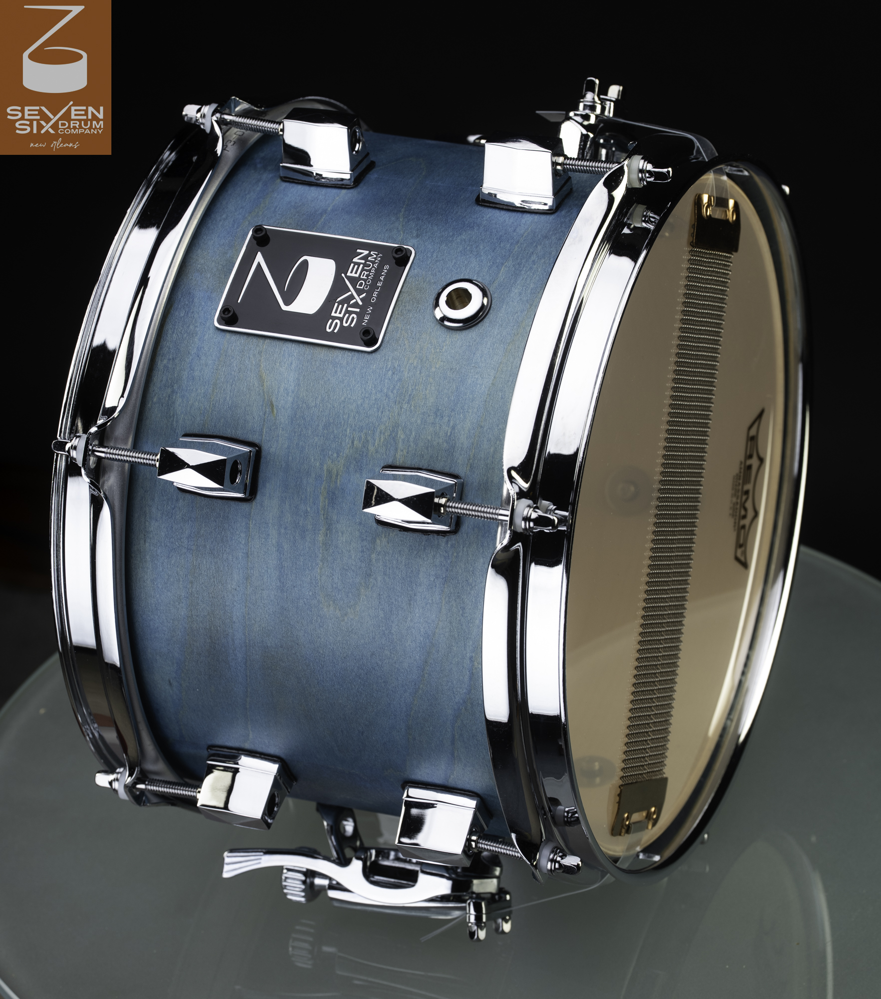 Handmade wood snare drum with a light blue stained finish, polished chrome hoops and lugs, and exposed snare wires.