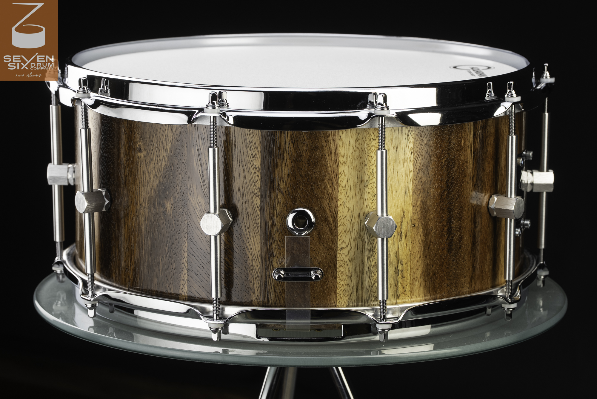 Handmade snare drum with a glossy natural-grain wood shell, chrome hoops, and hexagonal tube lugs.
