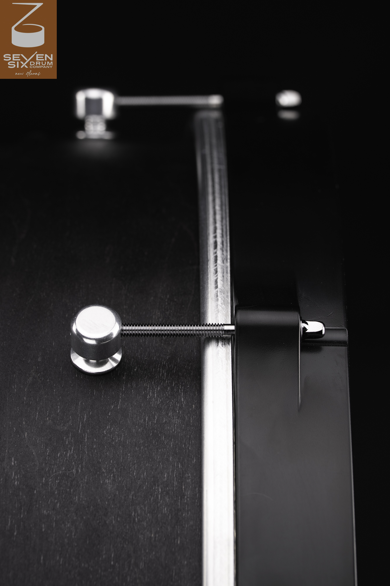 Matte black wood snare drum shell featuring a chrome tension rod, cylindrical silver lug, and black hoop.