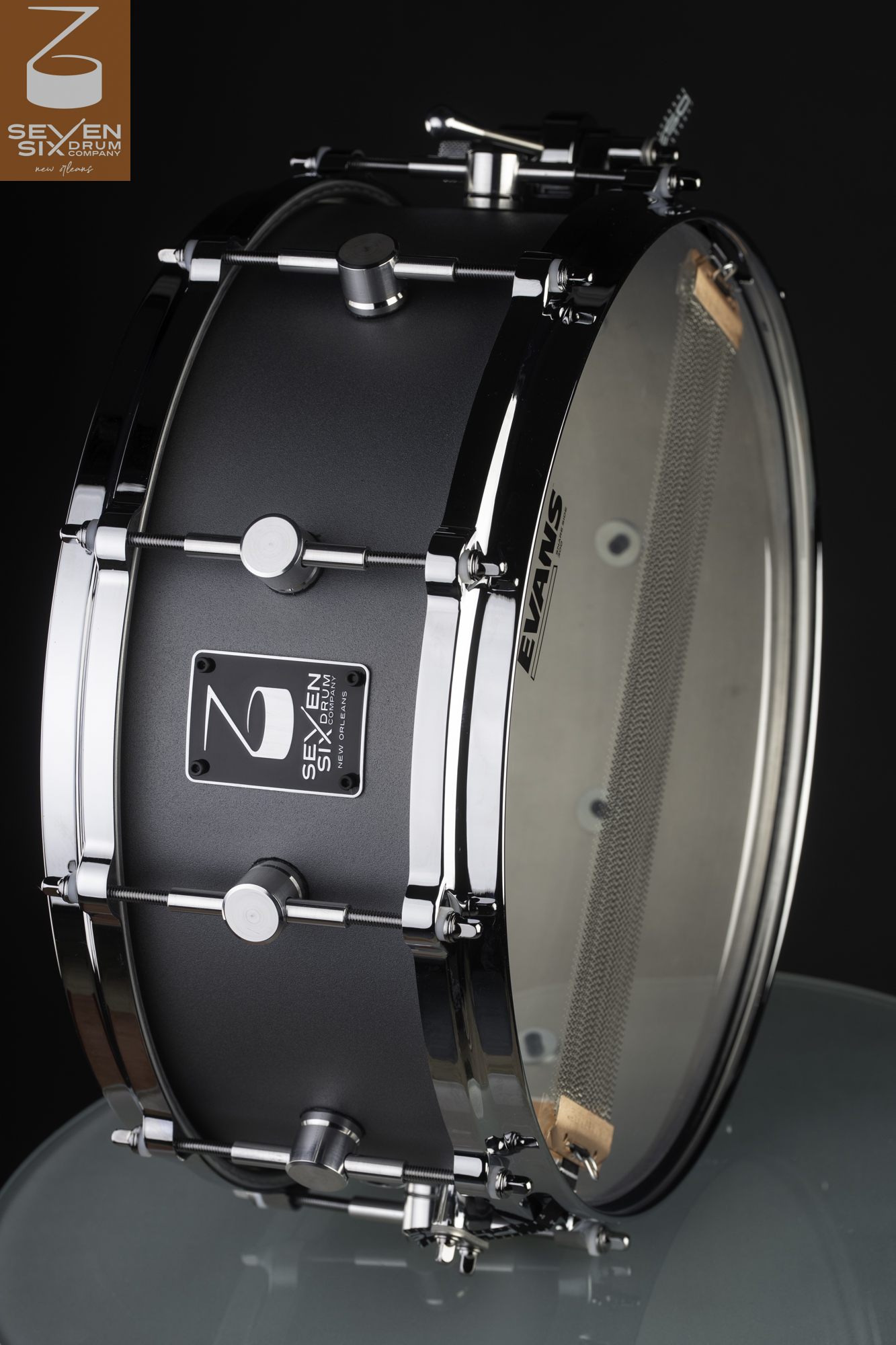 Handmade snare drum featuring a matte gray shell, polished chrome hoops, round single-point lugs, and snare wires.