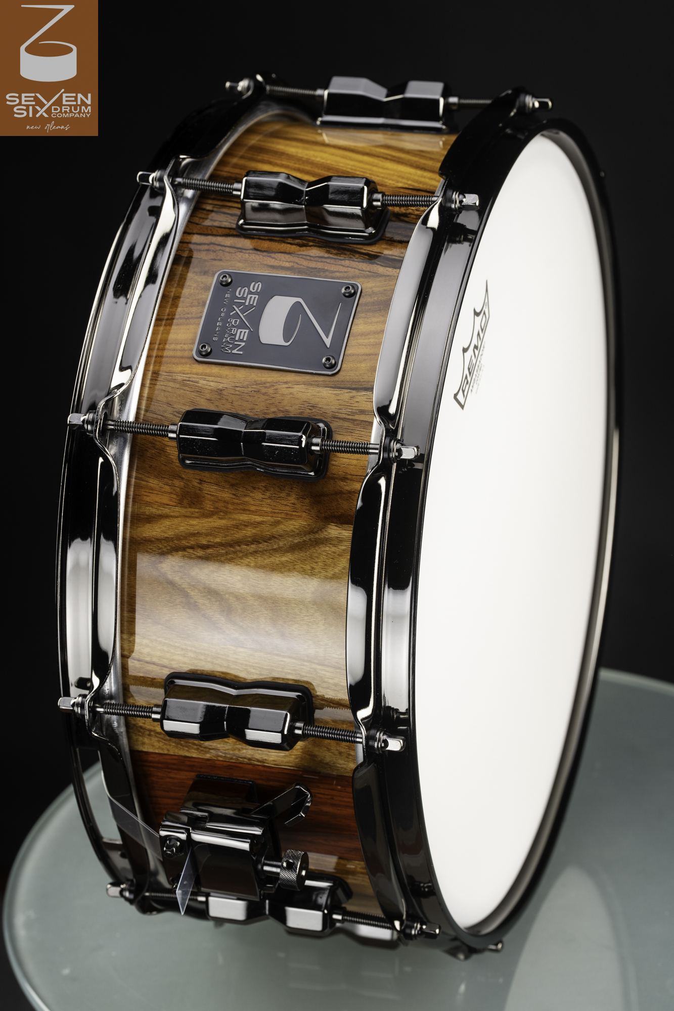 Handcrafted snare drum with a high-gloss natural wood finish and sleek black nickel hoops and lugs.