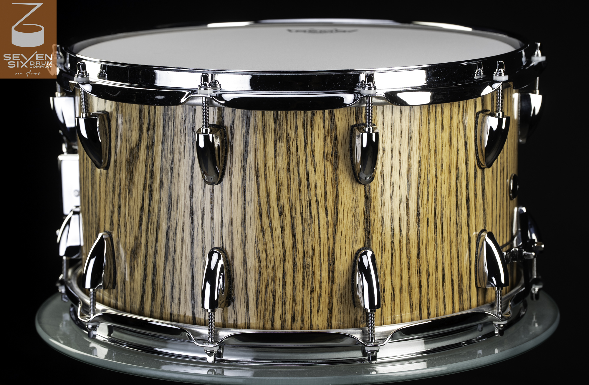 Handmade snare drum featuring a natural zebrawood finish, polished chrome teardrop lugs, and matching hoops.