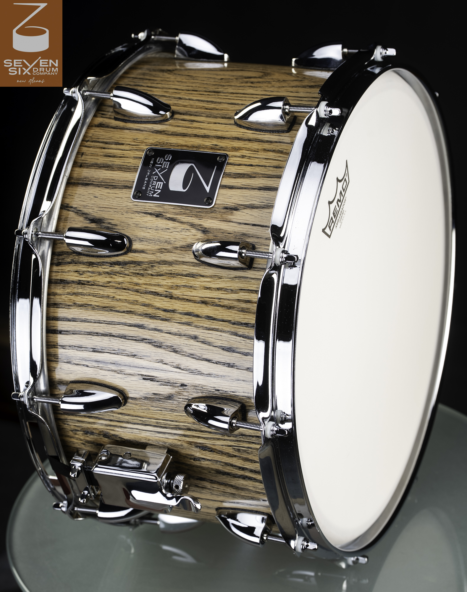 Natural wood snare drum with a prominent grain, polished chrome hoops, bullet lugs, and throw-off.