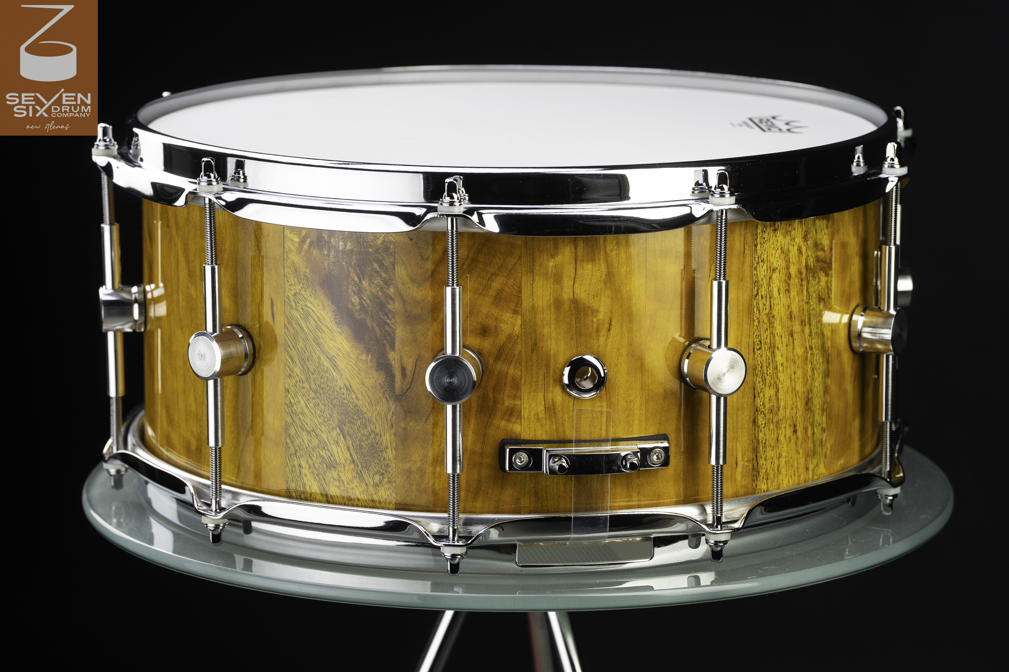 Handmade snare drum with a glossy golden wood stave shell, polished chrome hoops, and center-mounted lugs.
