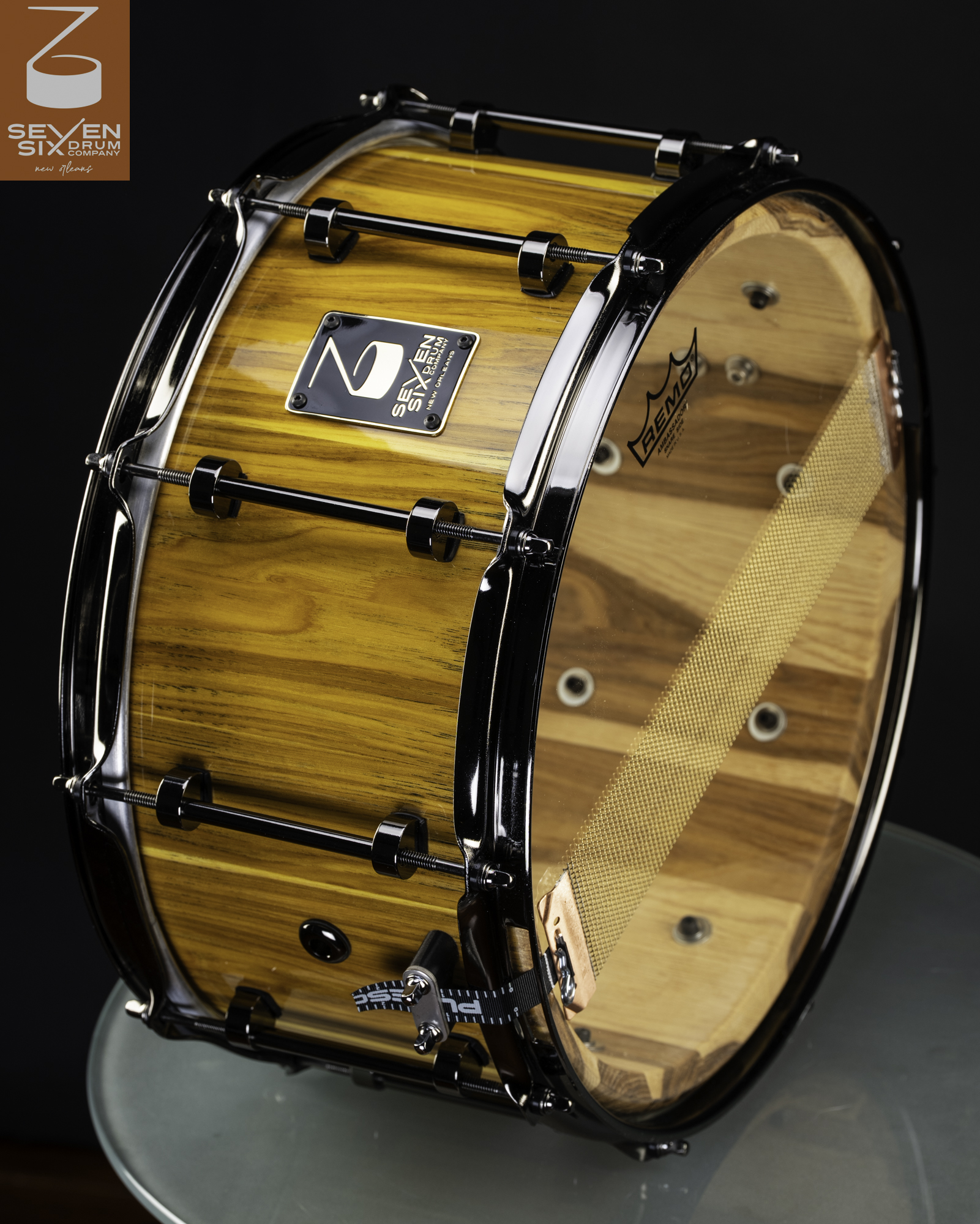 Handcrafted wood snare drum with a high-gloss natural finish, black nickel tube lugs, black hoops, and brass snare wires.