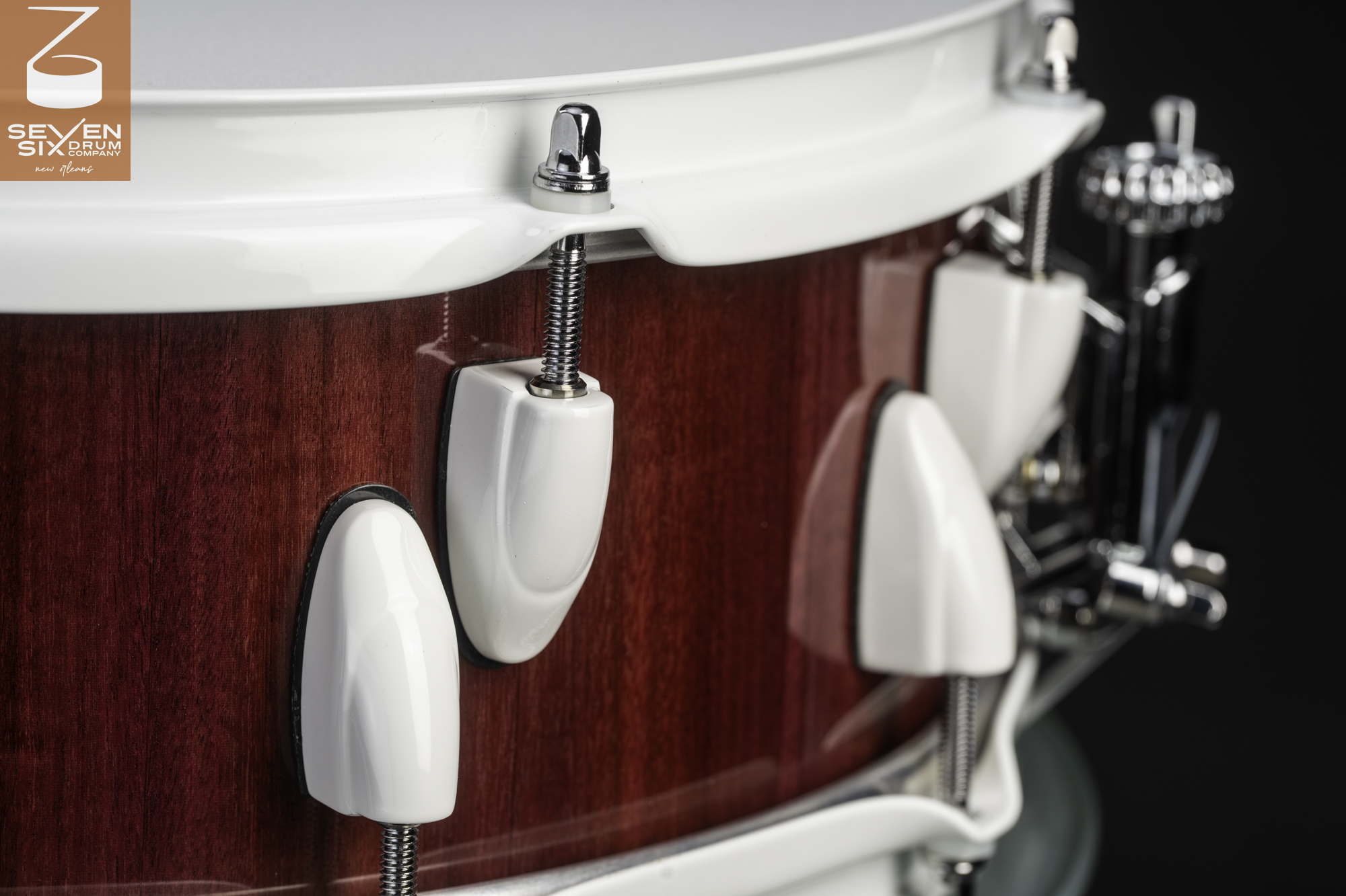 Handmade snare drum featuring a glossy red wood shell, white hoops, and matching white lugs.