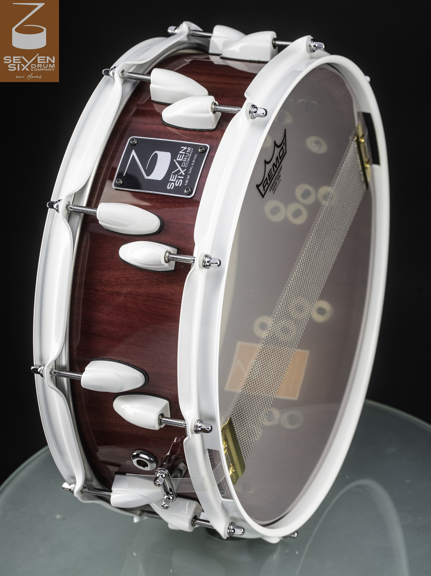 Handmade snare drum with a glossy red wood shell, contrasting white rims and lugs, and wide snare wires.