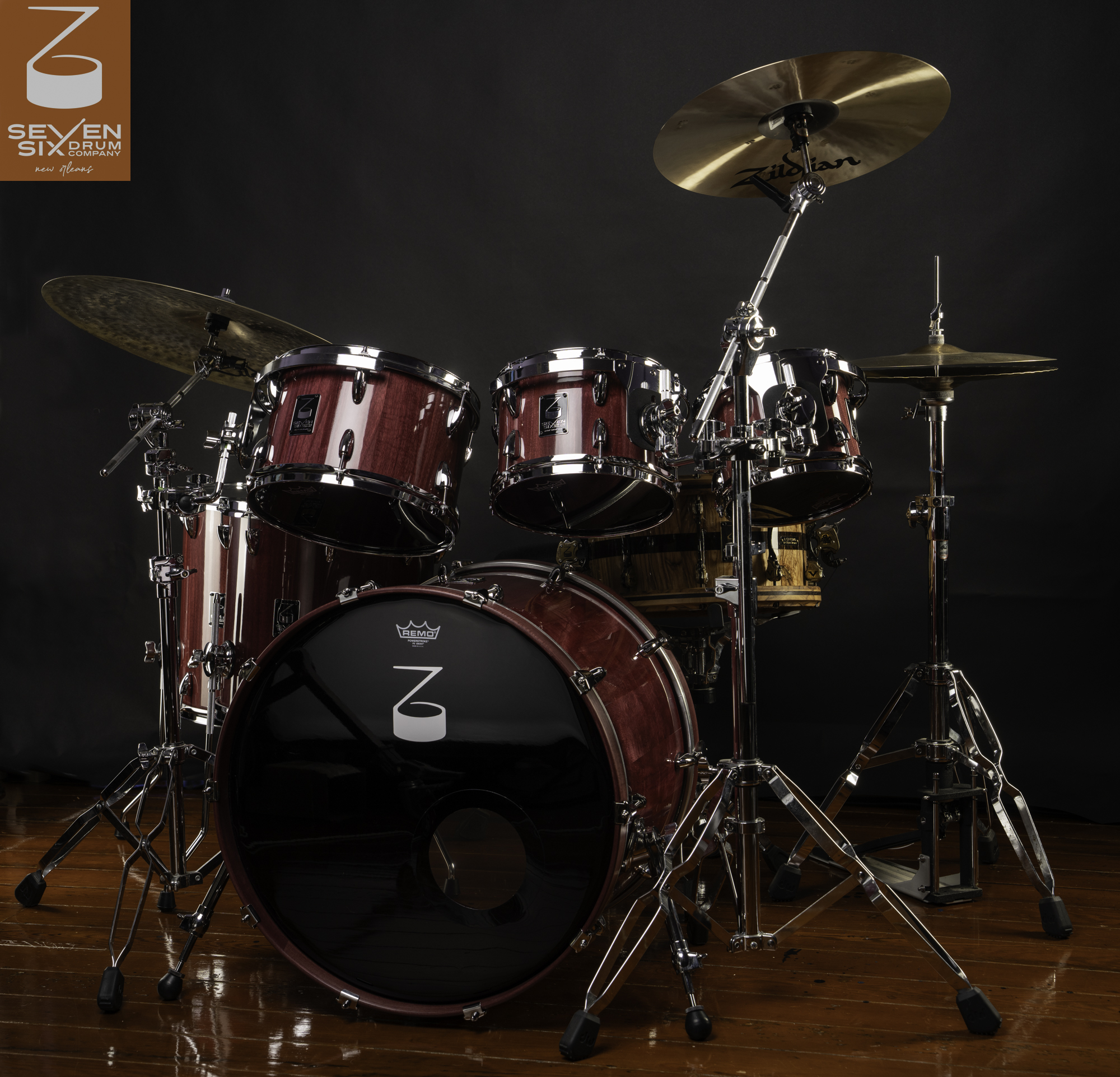 Drum set with Purpleheart wood shells, a natural wood snare drum, cymbals, and chrome hardware on a wooden floor.