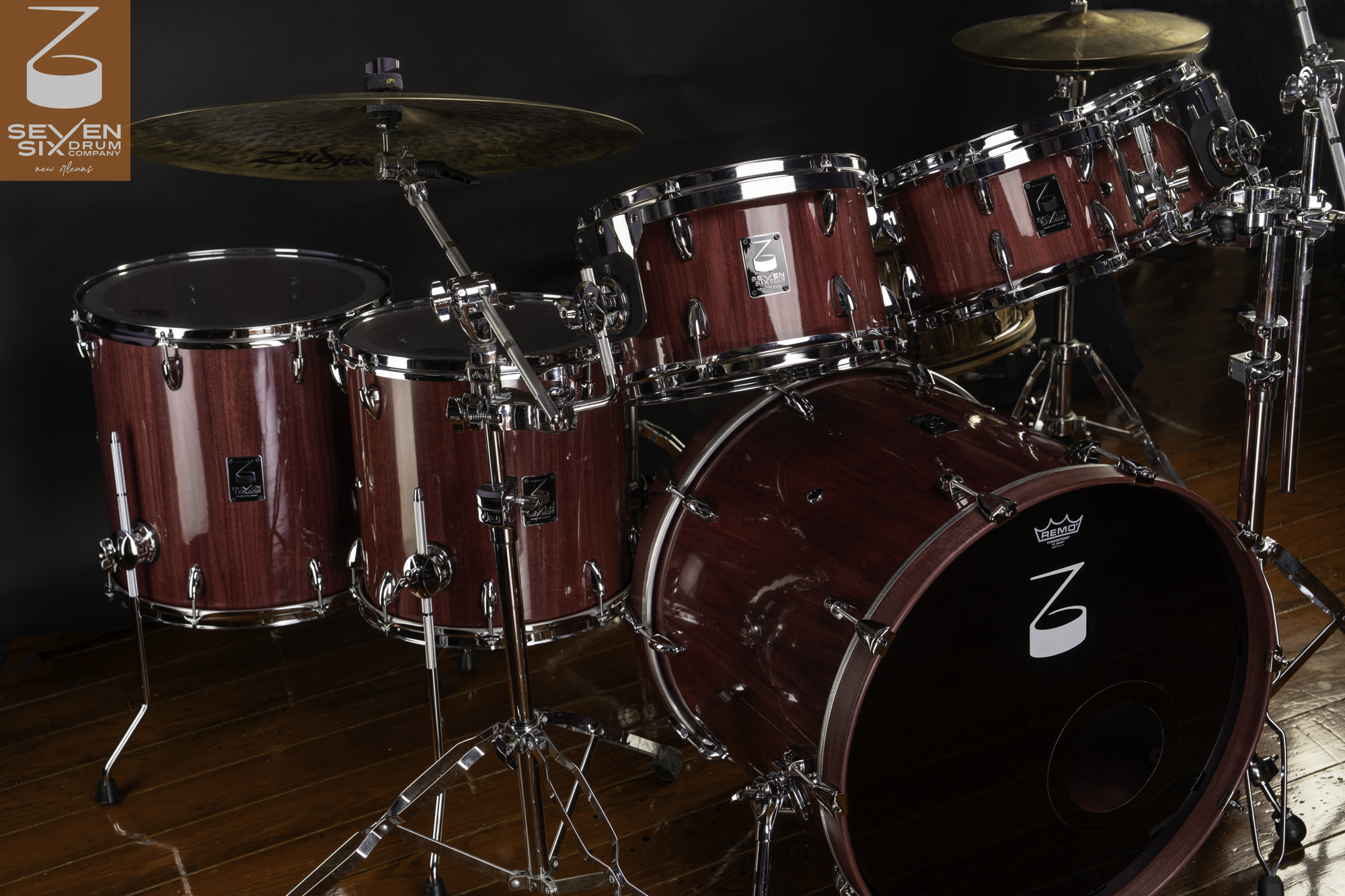 Custom drum set in a glossy purpleheart wood finish with polished chrome hardware, rims, and cymbal stands.