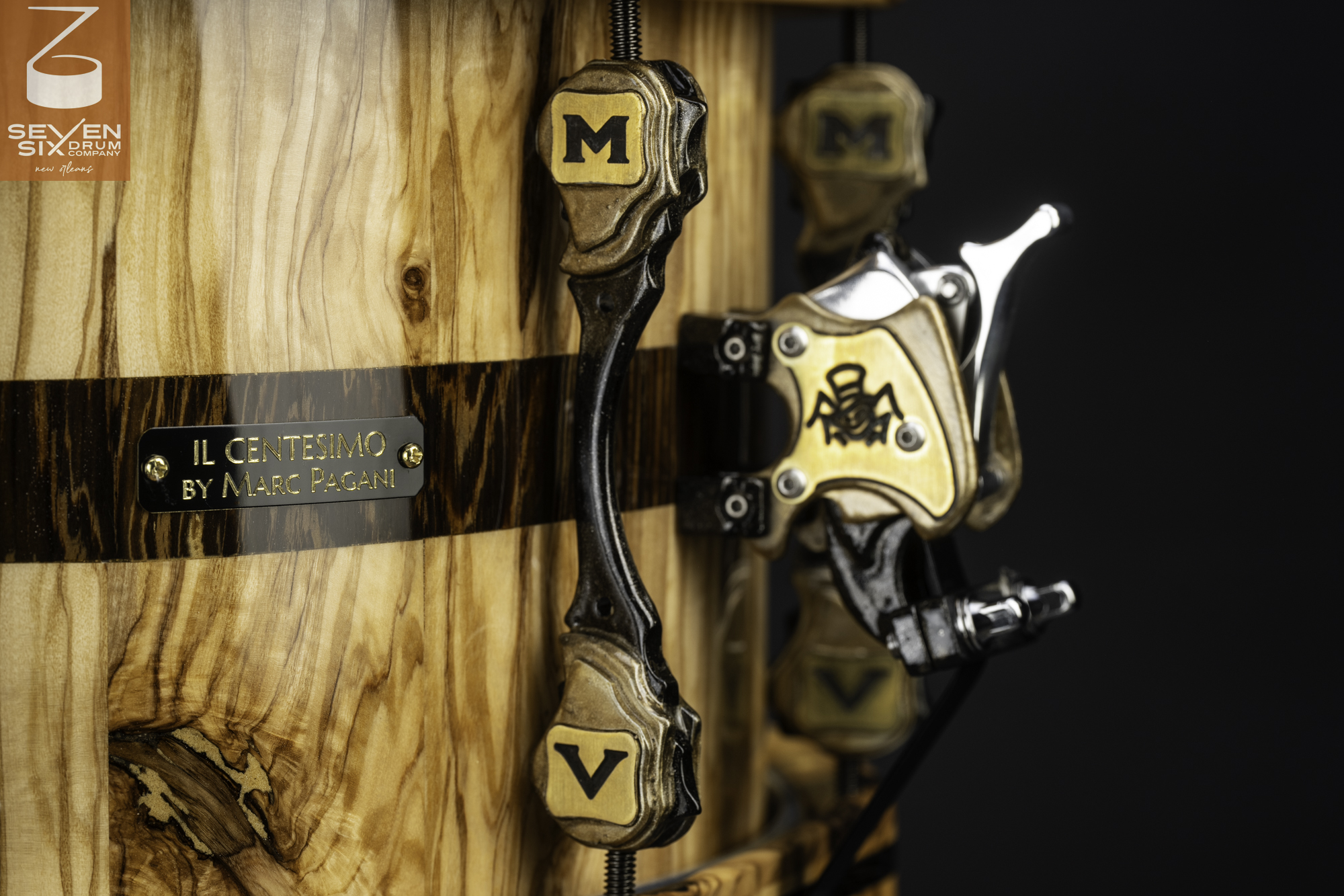 Glossy natural wood snare drum featuring a dark inlay stripe, custom brass lugs, and a snare throw-off mechanism.