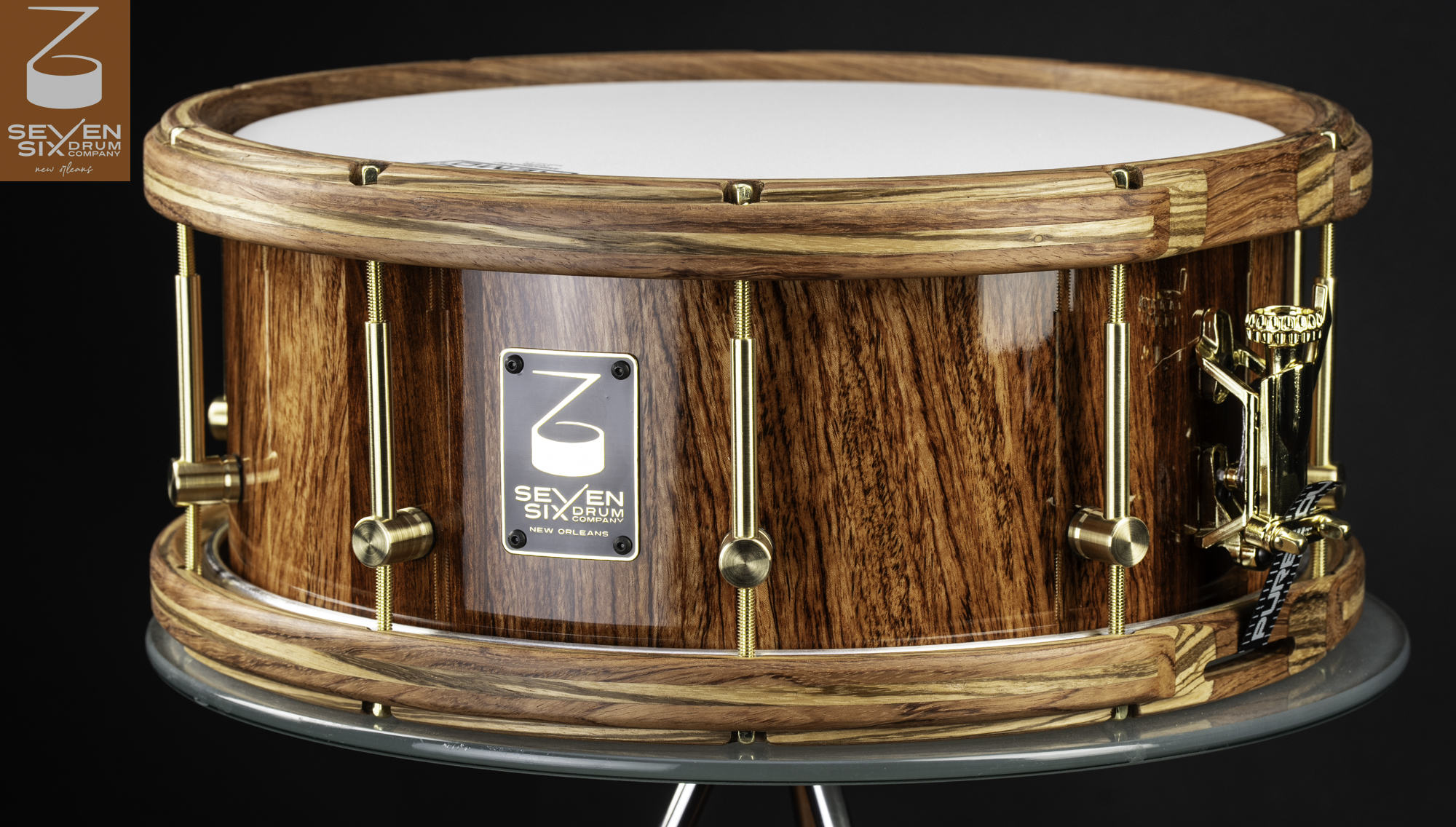Handmade Bubinga snare drum with a glossy natural Bubinga  shell, matching Bubinga and Zebrawood hoops, and brass tube lugs.