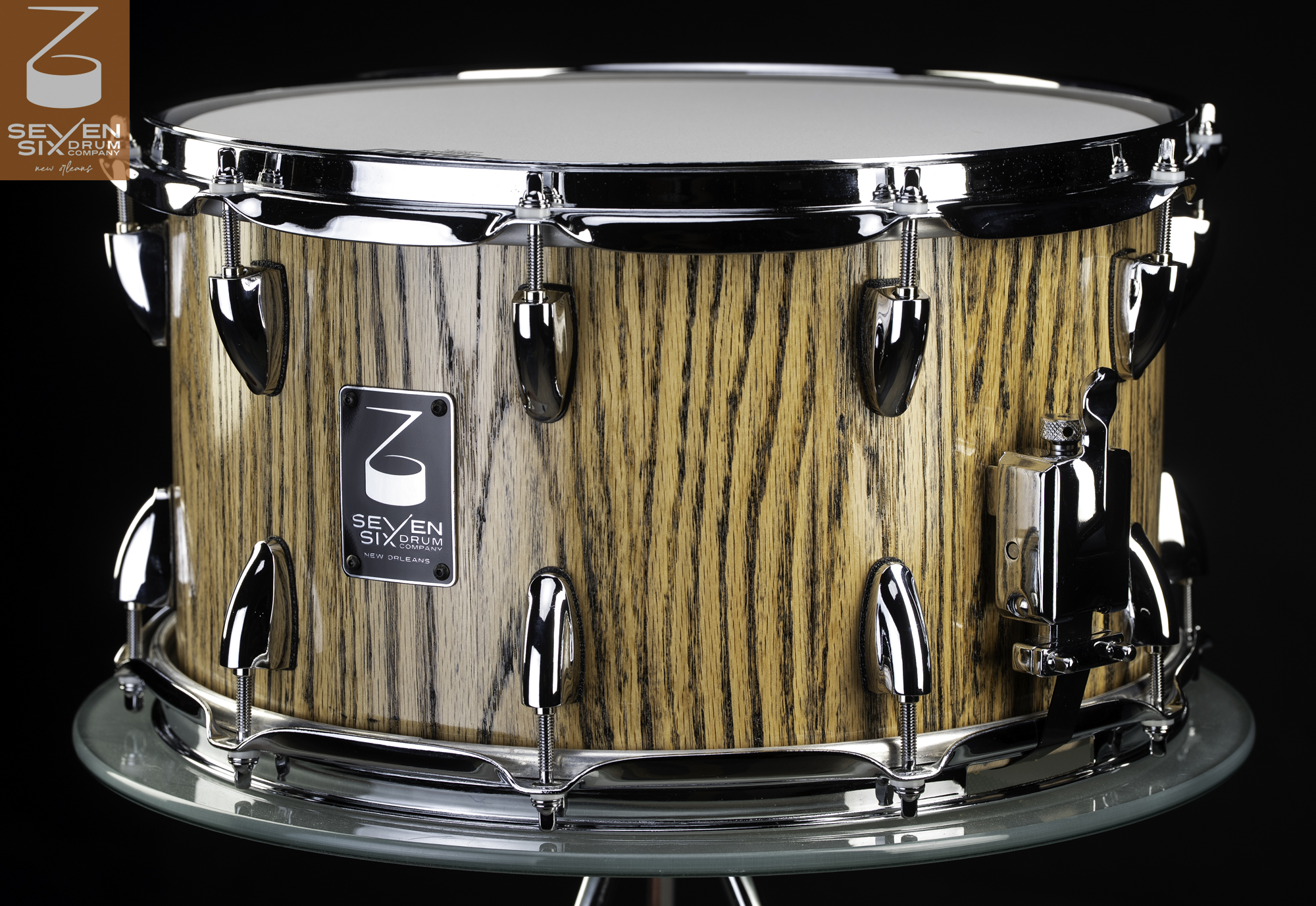 Handmade red oak snare drum with a glossy striped wood shell, chrome hoops, teardrop lugs, and a throw-off.